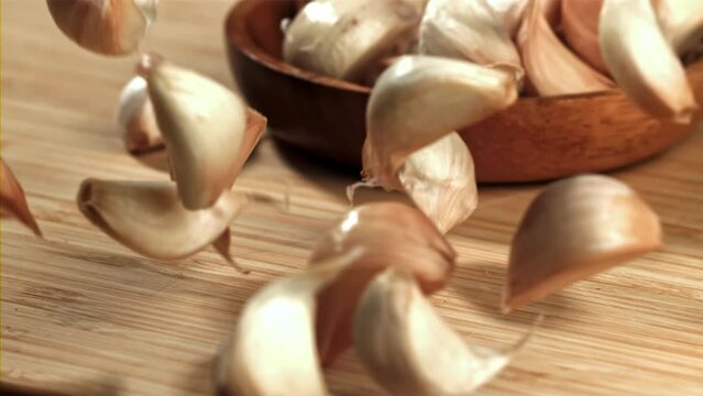 Fresh garlic falls on a cutting board. Filmed on a high-speed camera at 1000 fps. High quality FullHD footage