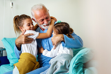Happy grandchildren visiting grandfather at hospital ward. Support, family and healthcare concept. - obrazy, fototapety, plakaty