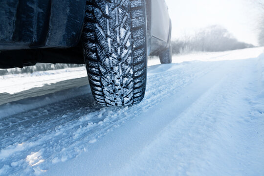 Car is on a snow-covered winter road. Сlose up of winter tire.