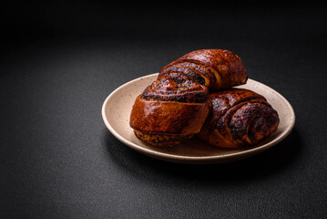 Delicious fresh sweet baked buns with poppy seeds and cinnamon on a ceramic plate