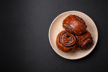 Delicious fresh sweet baked buns with poppy seeds and cinnamon on a ceramic plate
