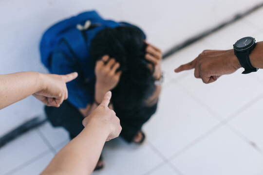 School goy getting bullied at school. Group of hands pointing finger to scared schoolboy.