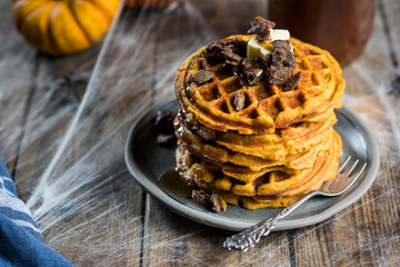 Stack of homemade pumpkin spice waffles with caramelized seeds and syrup