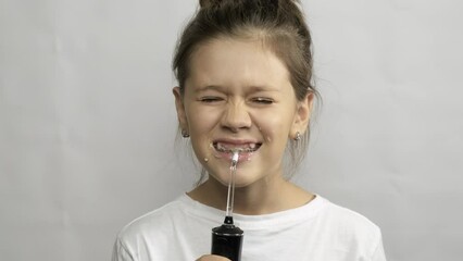 A child brushes his teeth with an irrigator. Oral hygiene. Gray background.