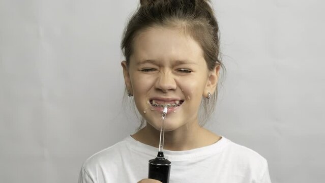 A child brushes his teeth with an irrigator. Oral hygiene. Gray background.