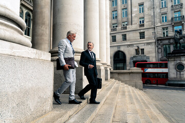 Businessmen moving down on steps near architectural columns