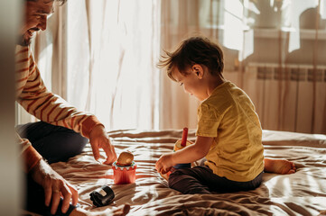 Cute boy playing with father on bed at home