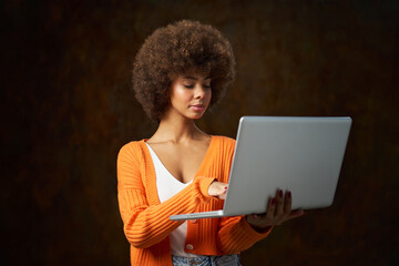 a young woman with afro hair with laptop computer photo in studio with dark background