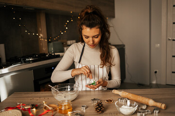 Happy caucasian carly woman cooking during winter holidays in cozy home kitchen, beautiful lady make traditional christmas gingerbread cookies on xmas day