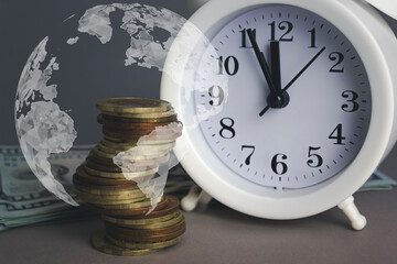 White alarmclock with Coins stack and stack of one hundred dollar bills with Digital Earth planet...