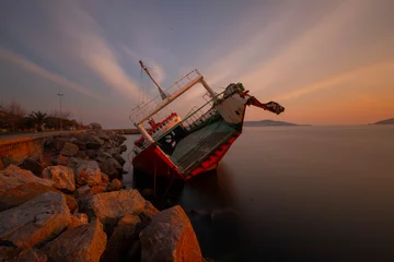 Fototapeten Sunken ship washed up on the seaside, sunset. © Samet