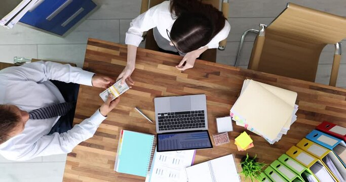 Businesswoman gives money to male partner at business meeting. Cash investment in promoting company and improving scope of activities. Teamwork upper view