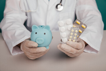 Healthcare finance. Doctor with blue piggy bank and pills in his hands