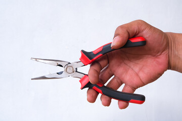 The hand of a man is holding a black red pliers isolated on the white background