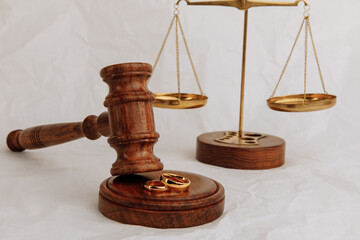 Judge's gavel with rings and scales on light background