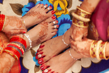 Indian Wedding Concept. Beautiful feet of two women in an Indian wedding, decorated with auspicious...
