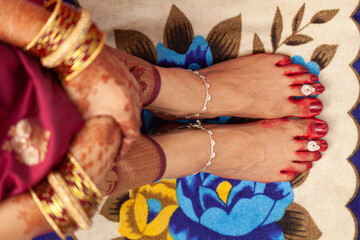 Indian Bengali Wedding Concept. Beautiful feet of an Indian bride, decorated with auspicious red...