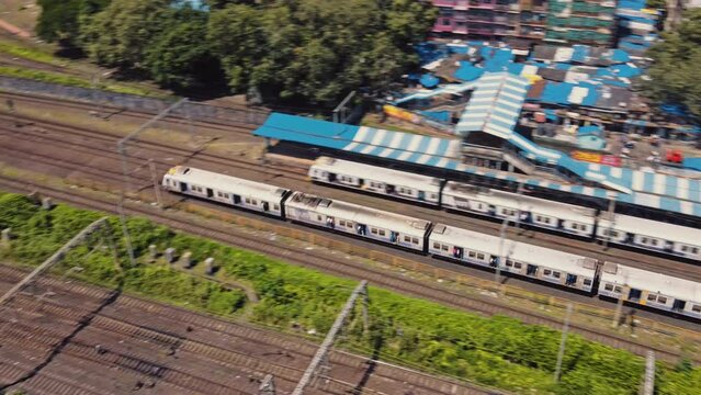 Cinematic aerial shot of moving Mumbai suburban trains or local trains in the morning on railway tracks. Skyline of Mumbai City, India. Developing India concept.