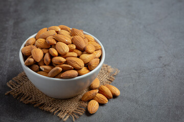 Almonds in bowl on dark grey background