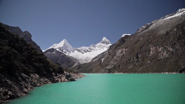beautiful turquoise water of the lake at laguna paron lagoon in the high andes mountains of the cordillera blanca at huascaran, Peru, with snow covered mountain peaks on a bright sunny day.