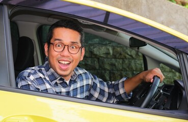 Adult Asian man showing wow face expression from inside a car - obrazy, fototapety, plakaty