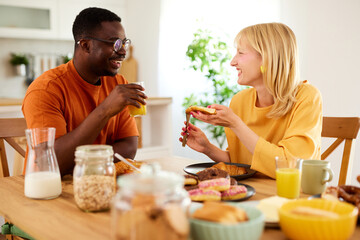 Multiracial couple enjoying breakfast together at home