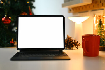 Blank display screen digital tablet and cup of hot chocolate on white table in decorated living...
