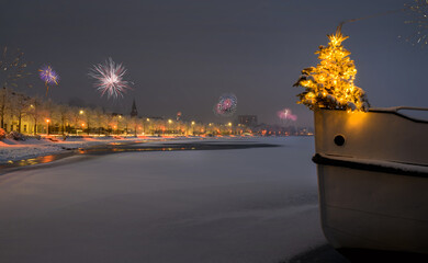 Christmas tree stands at the edge of the bow of a boat and firewors in the background. Silvester...