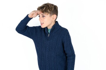 Caucasian teen boy very happy and smiling looking far away with hand over head. Searching concept.