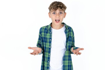 Frustrated Caucasian teen boy feels puzzled and hesitant, shrugs shoulders in bewilderment, keeps mouth widely opened, doesn't know what to do.