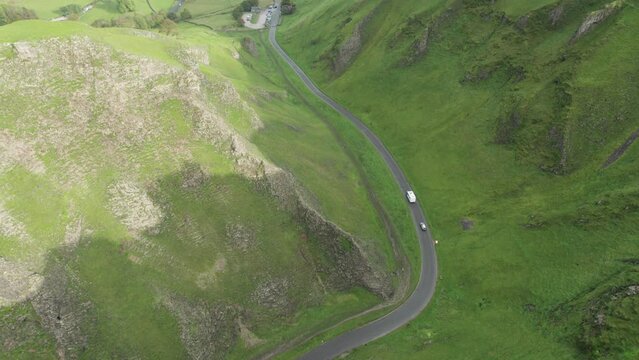 Motorhome driving down narrow road through Winnats Pass, Peak District, England. Aerial landscape in 4K