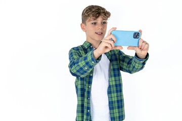 caucasian kid boy wearing plaid shirt taking a selfie to post it on social media or having a video...