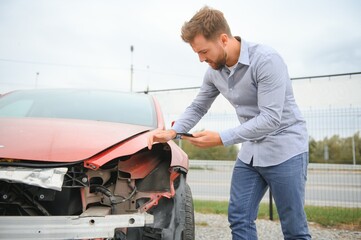 Young man driver in car accident near broken car on the road after a car accident