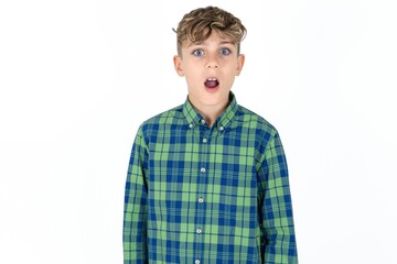 Shocked caucasian kid boy wearing plaid shirt stares bugged eyes keeps mouth opened has surprised expression. Omg concept