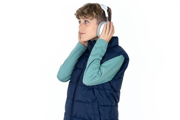  caucasian kid boy wearing blue vest  wears stereo headphones listens music concentrated aside. People hobby lifestyle concept