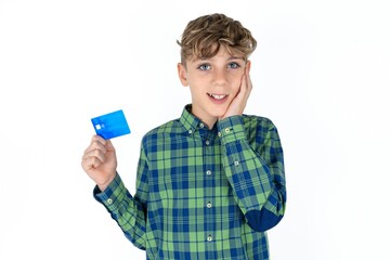 Astonished positive caucasian kid boy wearing plaid shirt arm face hold bank plastic card impressed functions