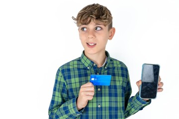 caucasian kid boy wearing plaid shirt holding bank card modern device looking empty space