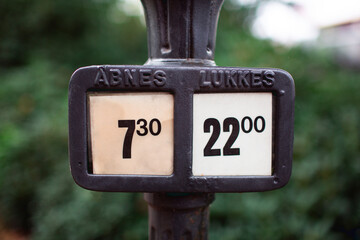 old cast iron street lamp with a box to show the opening and closing times of a park in the city of...