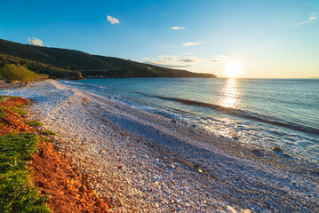 Sunset view beautiful beach and water bay in the greek spectacular coast line. Turquoise blue water...