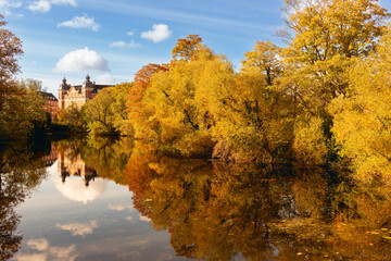 Trees in autumn reflected in the river. In warm yellow and orange colors