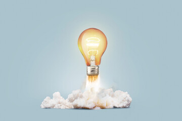 Creative light bulb rocket with blast and smoke takes off on a blue background, concept. Successful launch and development, creative idea. Think differently. Creative generator. Smart and thinking - obrazy, fototapety, plakaty