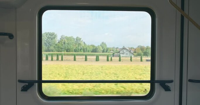 Close up, moving train window with summer nature view. Bright green countryside view from train window in sunny spring. Wagon inside in speed move. Travel by public transport. Nobody. Train motion