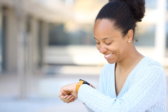 Black woman checking smartwatch smiling