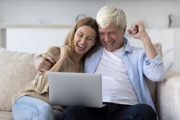 Excited happy senior dad and laughing cheerful adult daughter watching sport broadcasting on...