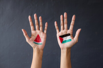 Hands painted with Palestine flag and slice of watermelon as symbol of support for Palestine.