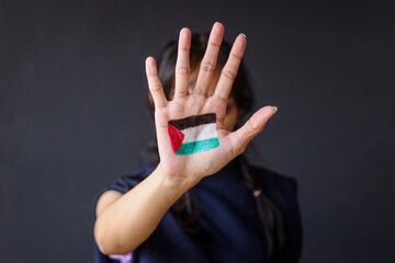 Woman showing hand painted with Palestine flag to the camera.  - obrazy, fototapety, plakaty