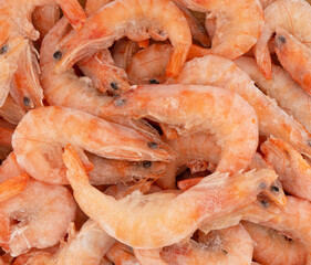 Raw frozen and peeled shrimp background. Pile of frozen shrimps. Close-up of frozen shrimps. A lot of royal shrimp macro shot