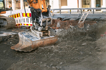 Fototapeta premium Close-up of big excavator on the urban construction site. Modern construction machinery at a construction site. Isolated scoop close up. Road construction. Architecture, engineering.