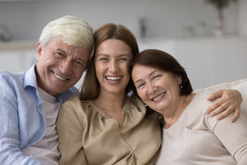 Positive caring senior parents and loving adult daughter woman enjoying leisure, closeness, sitting...