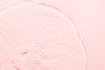 Water pink surface abstract background. Waves and ripples texture of cosmetic aqua moisturizer with...